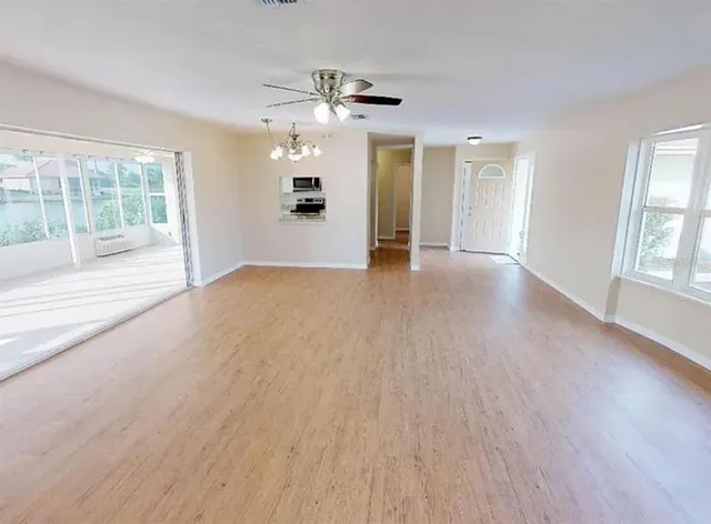 a view of an empty room with a window and wooden floor
