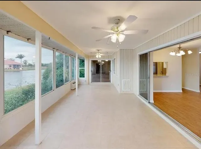 a view of an empty room with window and a kitchen view