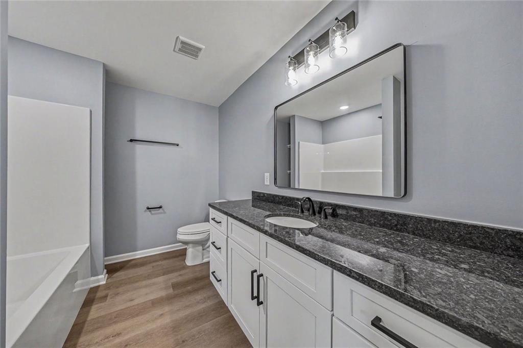 411 Hardy Avenue Southwest Rome, GA 30161 - Photo 16 of 27 a spacious bathroom with a granite countertop sink a toilet and a mirror
