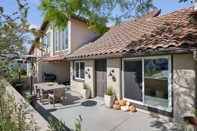 a view of a patio with table and chairs potted plants and floor to ceiling window