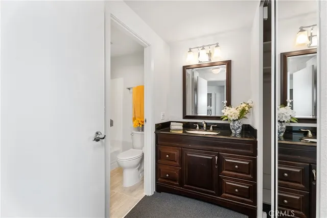 a bathroom with a granite countertop sink a toilet and a mirror