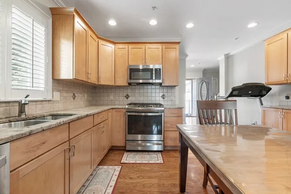 a kitchen with stainless steel appliances granite countertop a stove a sink and a microwave