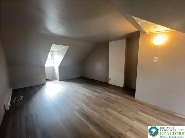 an empty room with wooden floor and windows with curtains