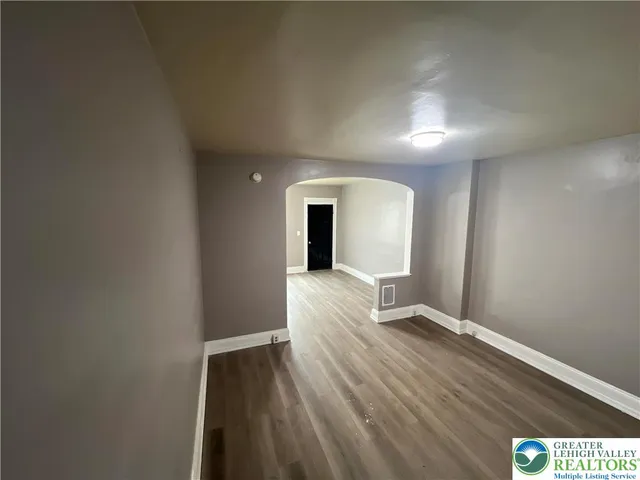 a view of a hallway with wooden floor and a living room