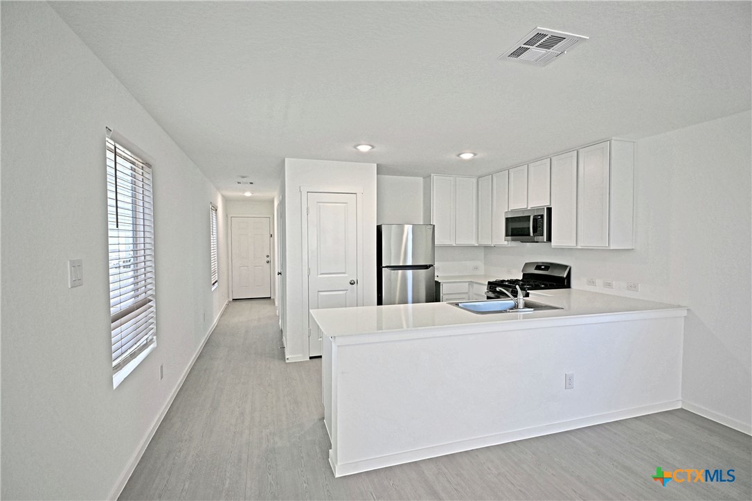 11822 Bluebell Ridge Converse, TX 78109 - Photo 5 of 24 a large white kitchen with stainless steel appliances a refrigerator a stove a microwave and a refrigerator