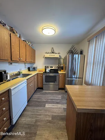 a large kitchen with stainless steel appliances granite countertop a stove a sink dishwasher and a refrigerator