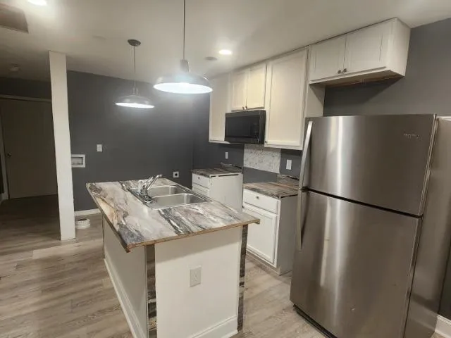 a kitchen with stainless steel appliances granite countertop a refrigerator a sink and a stove