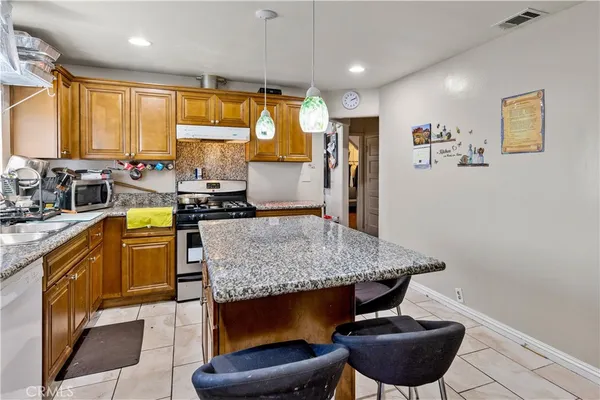 a kitchen with stainless steel appliances granite countertop a stove a sink and a refrigerator