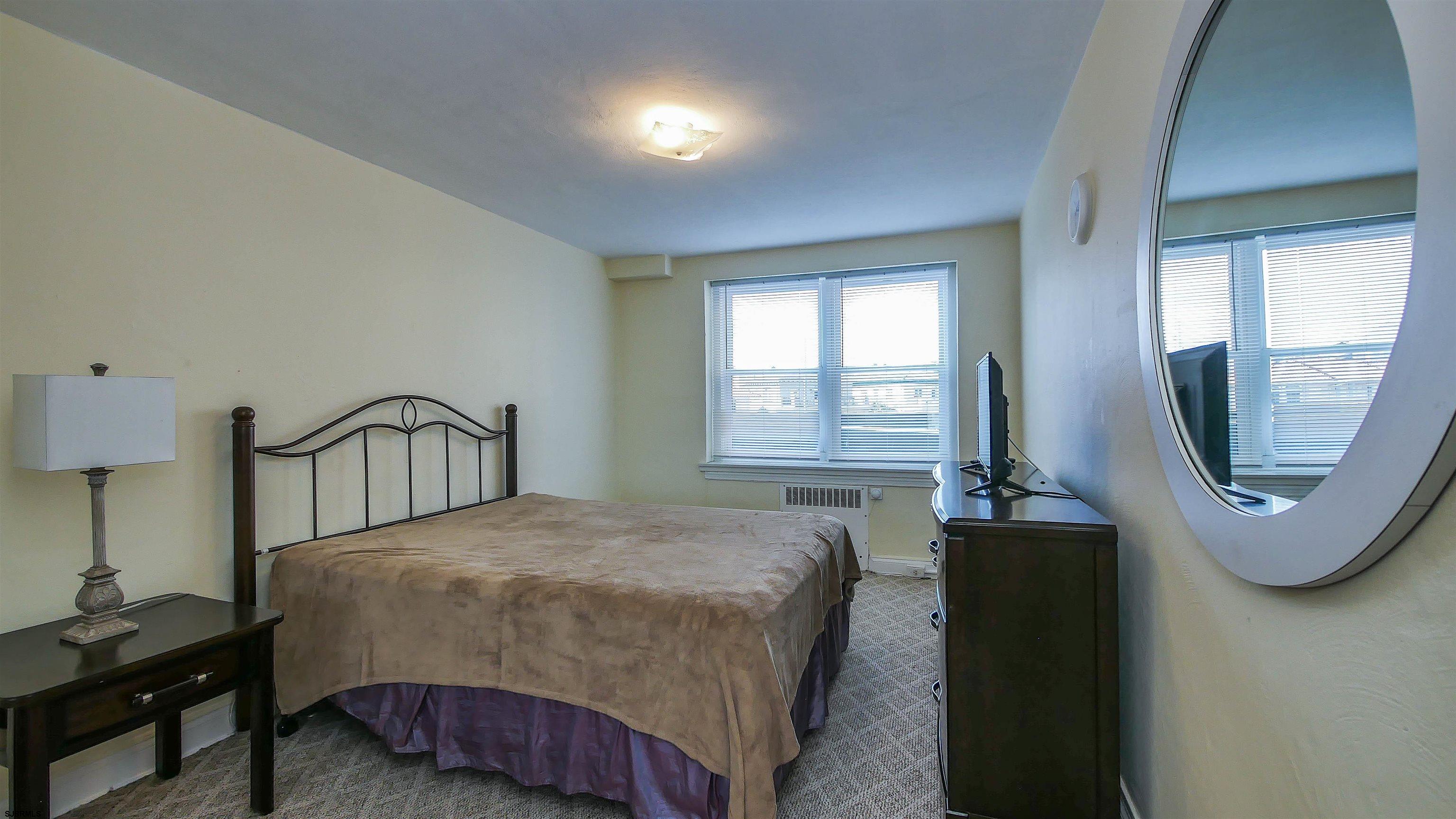 101 South Raleigh Avenue, Unit 207 Atlantic City, NJ 08401 - Photo 19 of 30 a bedroom with a bed a mirror and a window