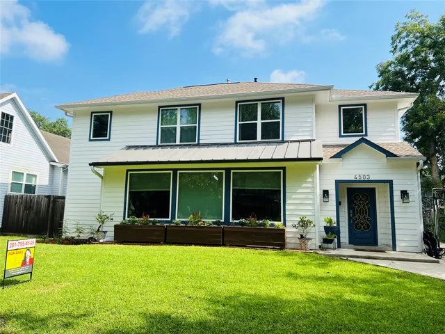 a view of a house with a yard and a large tree