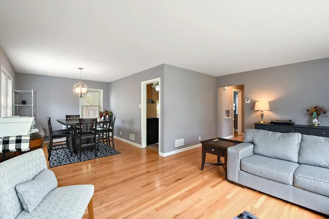a living room with furniture and a dining table with wooden floor