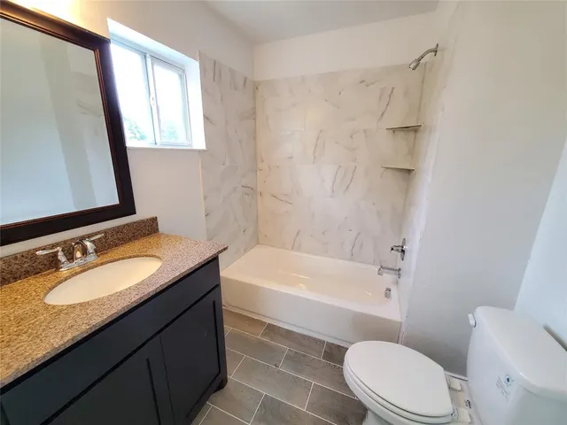 a bathroom with a granite countertop sink toilet mirror and bathtub