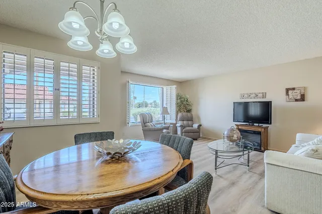 a dining room with wooden floor a chandelier a glass table and chairs