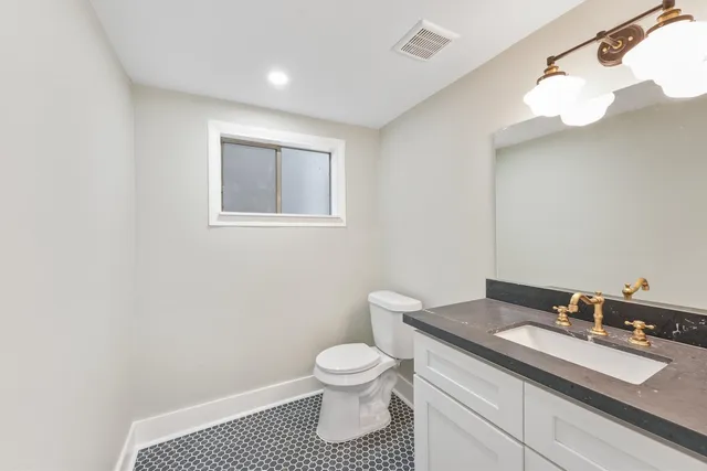 a bathroom with a granite countertop sink a toilet and a mirror