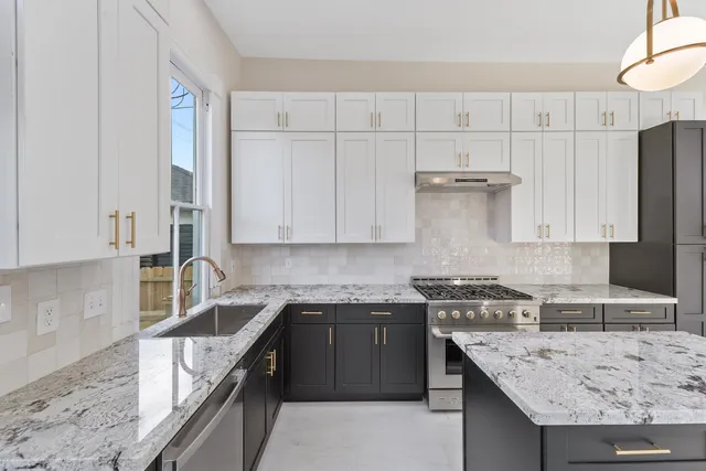 a kitchen with granite countertop a sink a stove and cabinets
