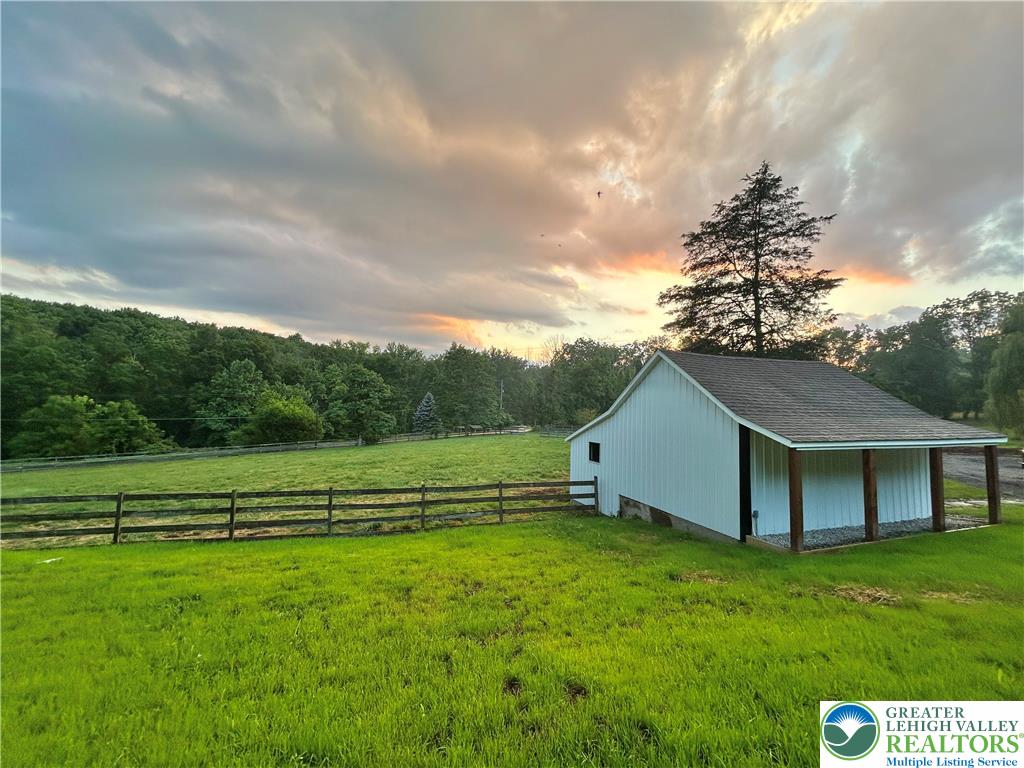 72 Allegheny Road Mount Bethel, PA 18343 - Photo 71 of 72 A picturesque barn, framed by verdant fields and distant trees, basks in the warm glow of a sunset sky.