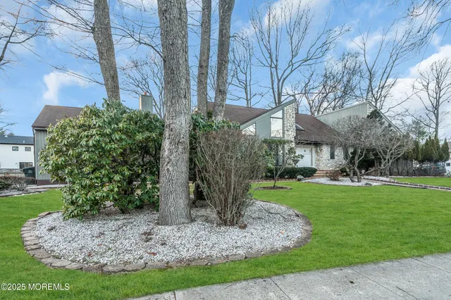 a front view of a house with garden and trees