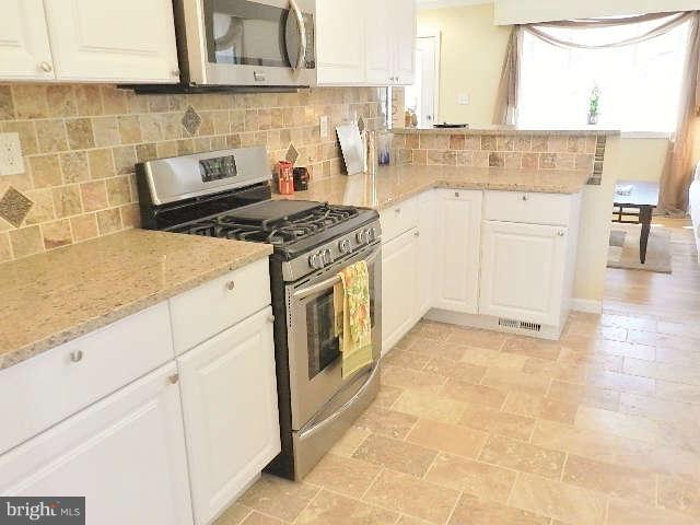 11611 Gail Street Silver Spring, MD 20902 - Photo 14 of 30 a kitchen with granite countertop a sink a stove and cabinets