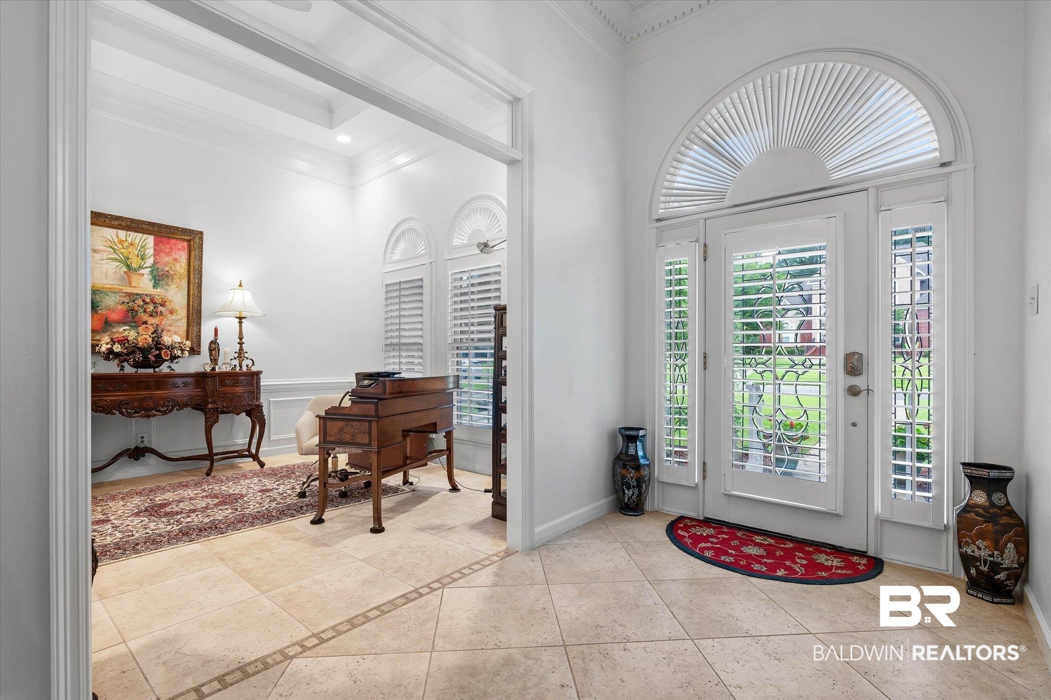 136 Old Mill Road Fairhope, AL 36532 - Photo 4 of 36 Entryway featuring tile flooring with decorative inlay, a white paneled front door with decorative glass, two side panels with plantation shutters, and an arched transom window with plantation shutters