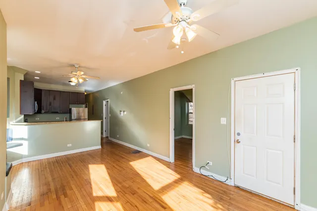 a view of an empty room and kitchen with a window wooden floor