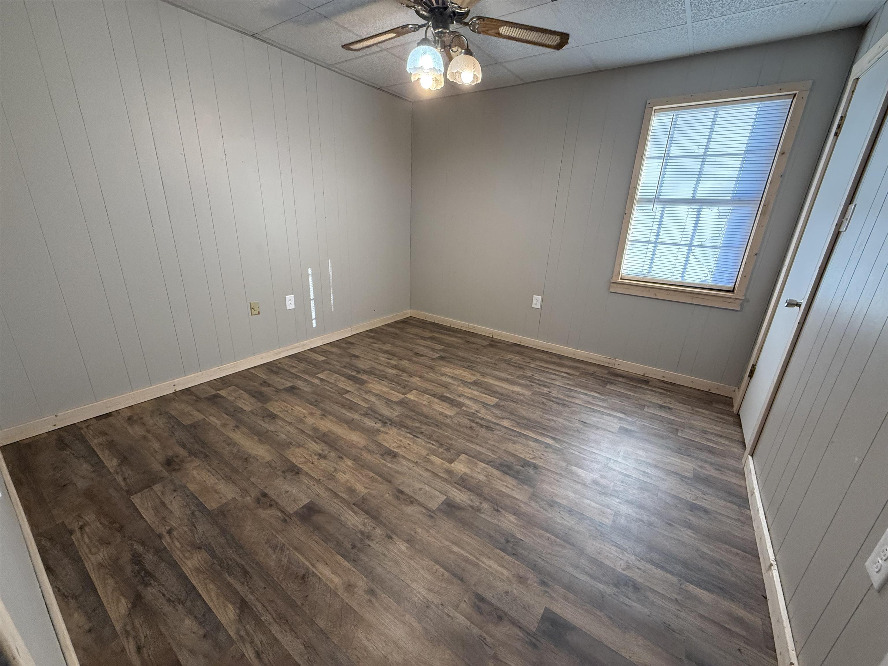 2142 Highway 70 Mason, TN 38049 - Photo 26 of 36 Spare room featuring wooden walls, ceiling fan, dark wood-style floors, and a paneled ceiling