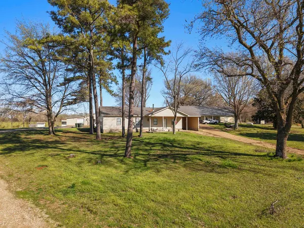 a view of a house with a big yard and large trees