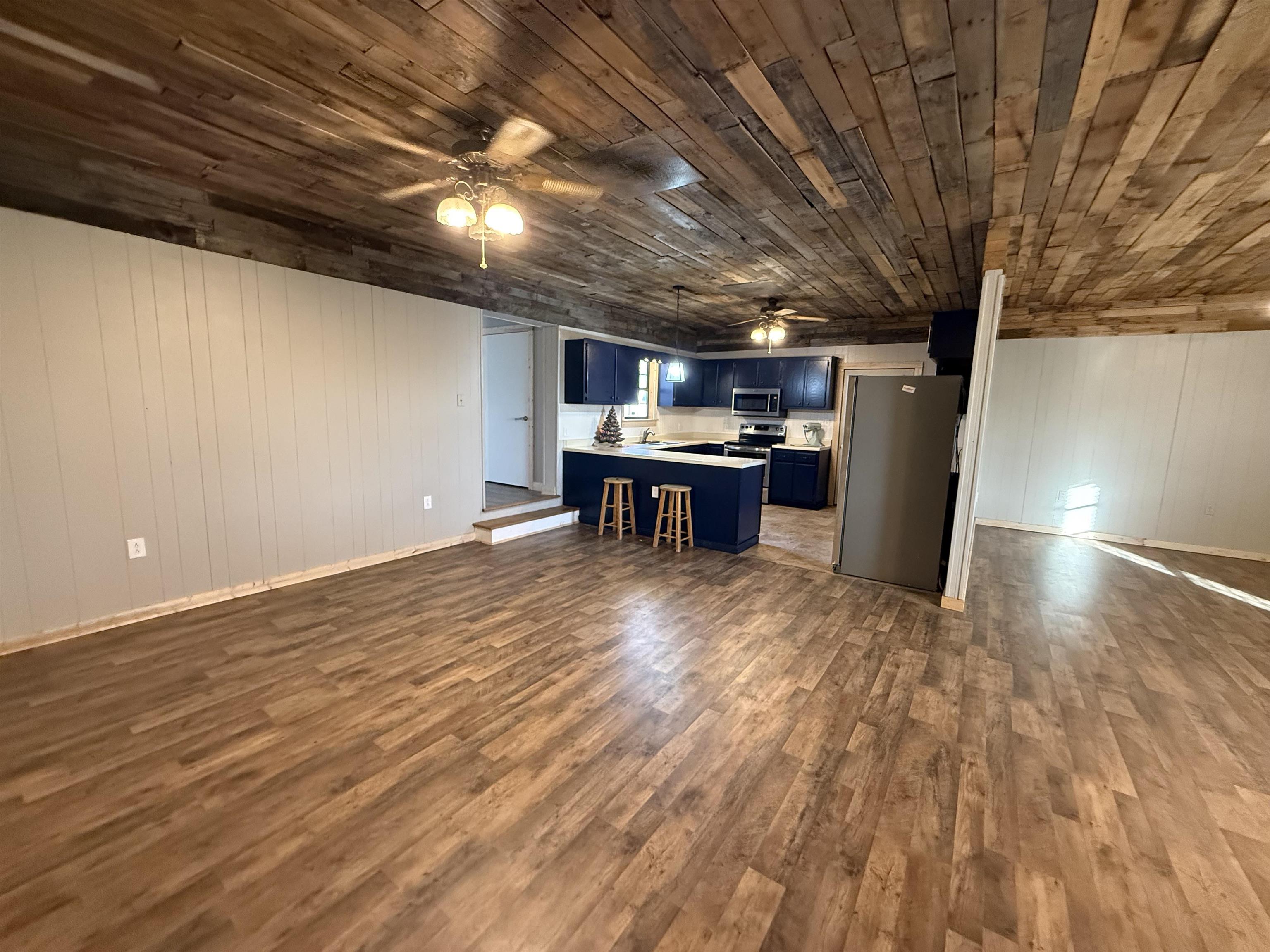 2142 Highway 70 Mason, TN 38049 - Photo 36 of 36 Kitchen with blue cabinetry, open floor plan, wood walls, a peninsula, and stainless steel appliances