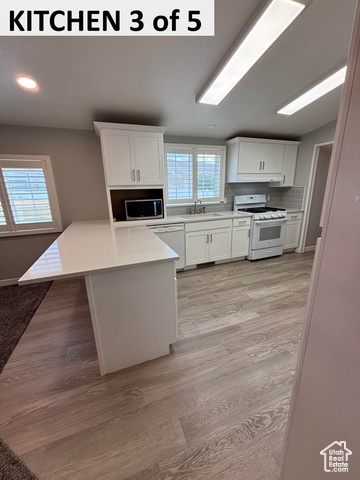 335 Memorial Park Road Henefer, UT 84033 - Photo 26 of 51 Kitchen featuring white cabinetry, decorative backsplash, white appliances, a peninsula, and light wood-style LVP floors