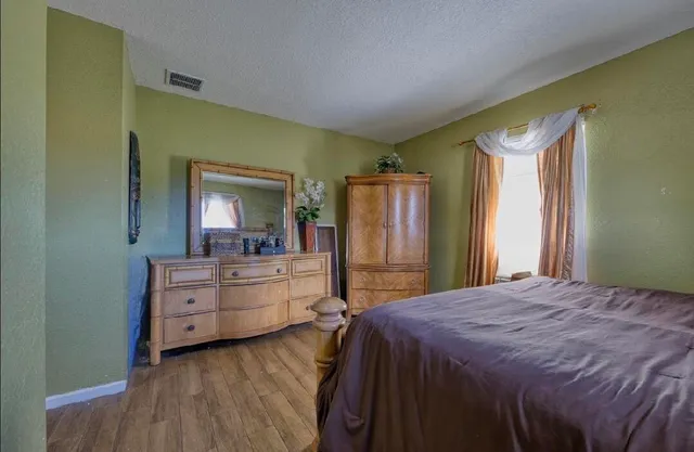 a spacious bedroom with a bed and a dresser