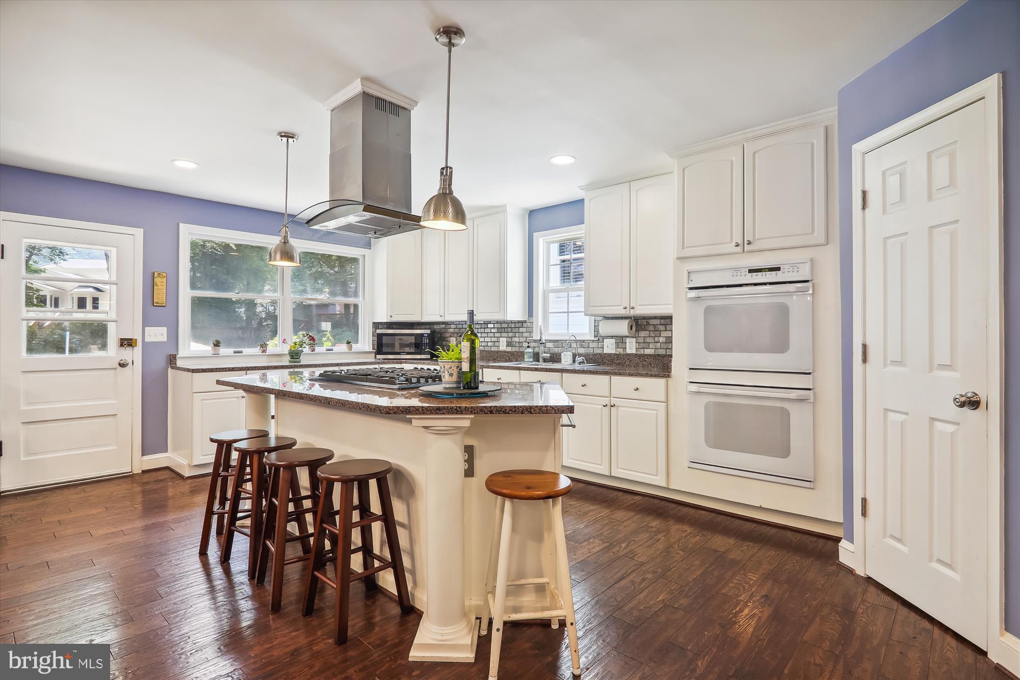 9805 Five Oaks Road Fairfax, VA 22031 - Photo 13 of 70 a kitchen with kitchen island granite countertop wooden floors and white appliances