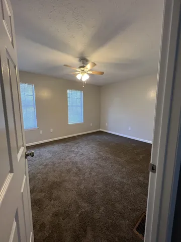 an empty room with windows and fan