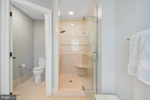 a spacious bedroom with a bed and dresser with wooden floor