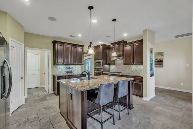 a kitchen with stainless steel appliances granite countertop a kitchen island a stove a table and chairs