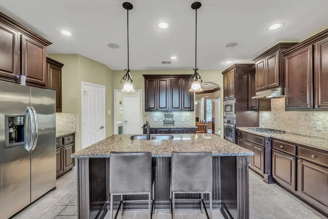 a kitchen with stainless steel appliances granite countertop a kitchen island a stove a table and chairs