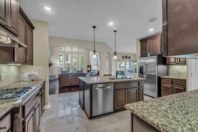 a kitchen with kitchen island granite countertop a sink counter top space appliances and cabinets