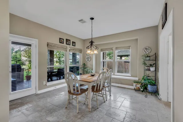 a dining room with furniture wooden floor a chandelier and a mirror