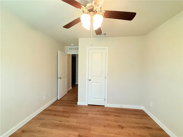 a view of an empty room and chandelier fan