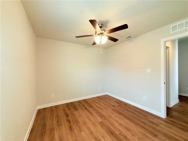 an empty room with wooden floor and a ceiling fan