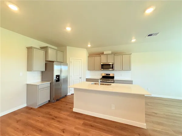 a kitchen with a refrigerator a stove top oven and white cabinets
