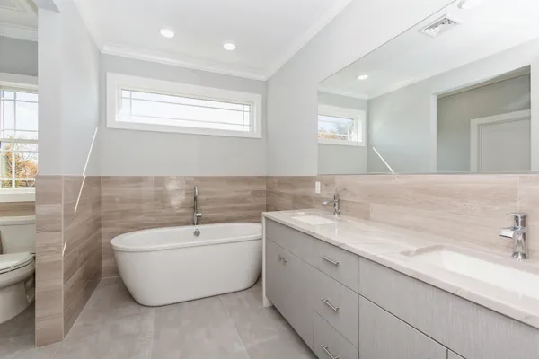 a spacious bathroom with a double vanity sink mirror and bathtub