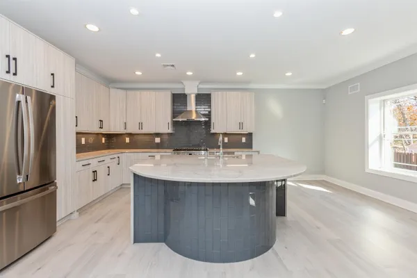 a kitchen with stainless steel appliances granite countertop a sink a microwave a refrigerator and white cabinets with wooden floor