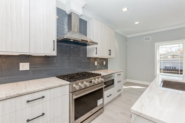 a kitchen with stainless steel appliances granite countertop a stove and a white cabinets