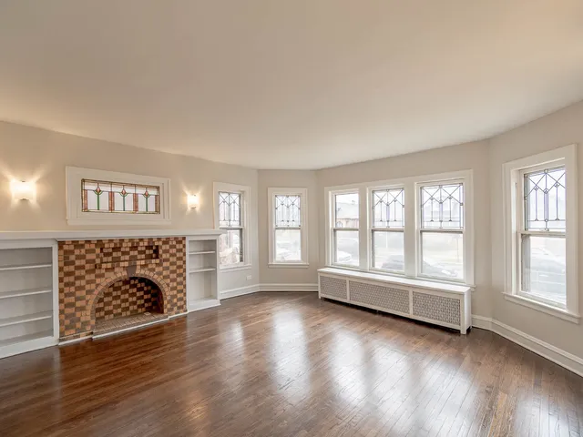 wooden floor fireplace and windows in an empty room