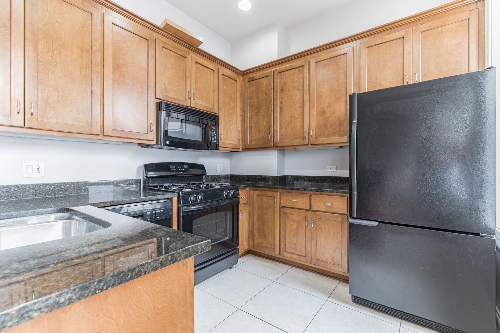 166 West Grand Avenue, Unit 3B Chicago, IL 60654 - Photo 6 of 16 a kitchen with granite countertop a refrigerator stove and sink with cabinets
