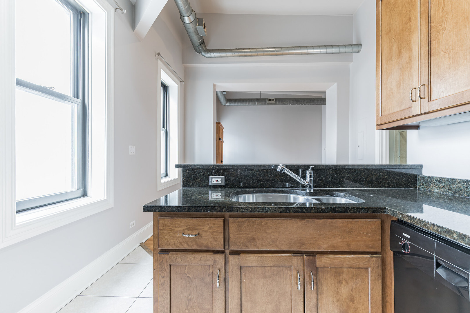 166 West Grand Avenue, Unit 3B Chicago, IL 60654 - Photo 9 of 16 a kitchen with kitchen island granite countertop a sink cabinets and stainless steel appliances