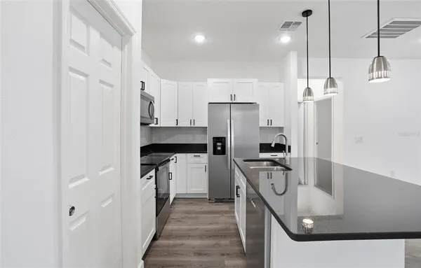 a kitchen with stainless steel appliances granite countertop a sink a stove and a refrigerator