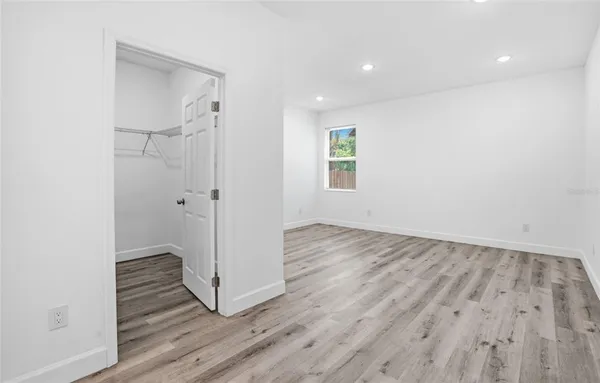a view of a hallway with wooden floor and closet