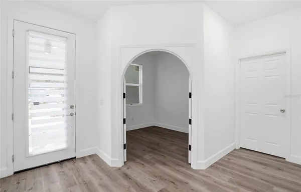 an empty room with wooden floor closet and windows