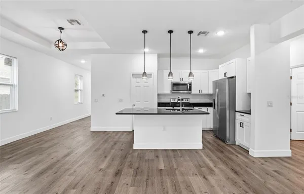 a kitchen with stainless steel appliances a refrigerator a sink and wooden floor