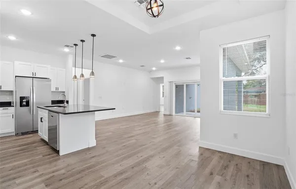 a kitchen with stainless steel appliances granite countertop a refrigerator a sink dishwasher a stove and a wooden floors